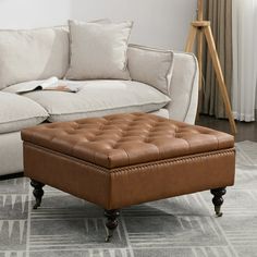 a living room with a white couch and brown footstool in front of a window