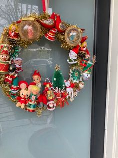 a christmas wreath hanging on the front door with ornaments around it and an ornament