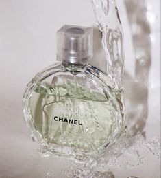 a bottle of chanel perfume sitting on top of a glass vase filled with water