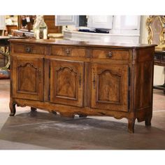 an old wooden sideboard with ornate carvings on the doors and drawers, in a room full of antique furniture