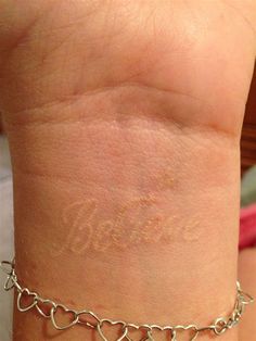 a close up of a person's arm with a bracelet on it and the word love written in cursive writing