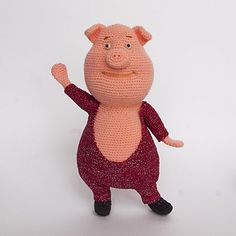 two small crocheted pigs standing next to each other on a white surface with one pointing at the camera