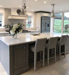 a large kitchen with an island in the middle and four chairs around it, along with windows