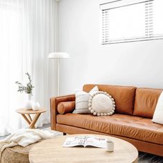 a living room with a brown leather couch and round coffee table in front of a window