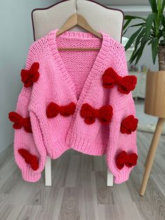 Big Red Bows Cardigan, Chunky Cropped Cardigan For Woman, Pink Sweater With Red Bows, Unique Gift For Women, Vintage, Handmade Our products are specially designed by our Mysisloops brand and are 100% original and 100% handmade. This carefully designed thick, soft art cardigan is made from a wool blend. The bow patterns on it are knitted with first-class  threads and sewn to the cardigan. All eyes will be on you and you will not want to take it off with this iconic wonderful design jacket that yo Red Knitted V-neck Outerwear, Red Knitted Winter Cardigan, Red Knitted Cardigan For Winter, Red Hand Knitted Long Sleeve Cardigan, Handmade Red Long Sleeve Cardigan, Handmade Red Winter Outerwear, Red Hand Knitted Winter Cardigan, Handmade Red Outerwear For Fall, Red Knitted Cardigan