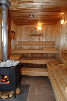 the inside of a wooden sauna with two benches and a fire place next to it