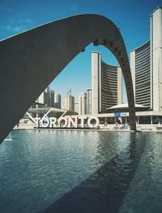 the word toronto is displayed in front of a body of water with tall buildings behind it