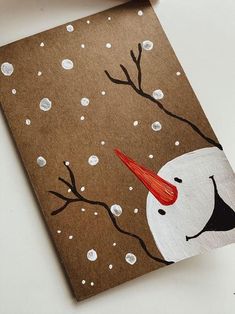 a brown card with a white snowman on it and red nose sticking out of the top