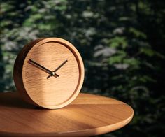 a small wooden clock sitting on top of a table next to a forest wallpaper