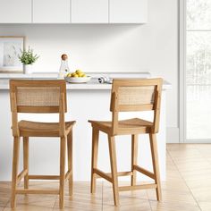 two wooden chairs sitting next to each other on a kitchen counter with an island in the background