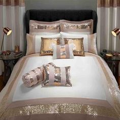 a bed with white and gold comforters on top of it