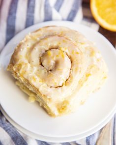 a close up of a plate of food with oranges in the background and a cinnamon roll