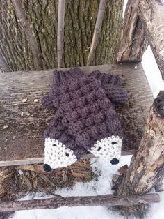 a crocheted hat sitting on top of a wooden bench next to a tree