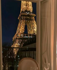 the eiffel tower lit up at night seen through an open window in a hotel room