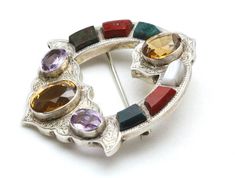 "-Intricate design Scottish brooch -Faceted oval cairngorm citrine, purple glass stones, and various agates adorn this pin -Pin is Sterling Silver, fine detailed silver work -Straight pin with rolling ball close -Stones measure 15mm x 12mm, 13mm x 10mm, and 10mm x 8mm -Agates measure roughly 8mm x 6mm -Pin measures roughly 2\" X 2.3\" -Weight 23.9g -Excellent vintage condition, ready to wear, silver has not been cleaned Very unique one of a kind piece to add to your collection" Traditional Gemstone Brooches As Gift, Oval Gemstone Brooch For Gift, Traditional Gemstone Brooches For Gift, Silver Oval Gemstone Brooches, Oval Multi-stone Brooches As Gift, Silver Oval Gemstone Brooch, Antique Oval Gemstone Brooches, Antique Multicolor Brooch Jewelry, Scottish Jewellery Vintage