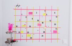 a desk with a calendar on the wall and pink sticky notes attached to the wall