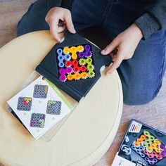 a person sitting on a chair holding a tray with beads in it and playing with them