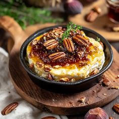 there is a small dish with some food in it on a wooden board next to nuts