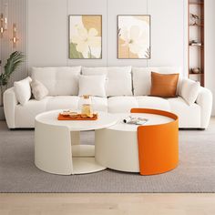 a modern living room with white furniture and orange accents on the coffee table in the center