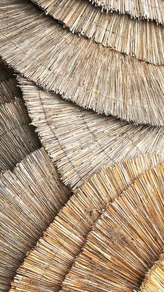 many straw umbrellas are stacked up together