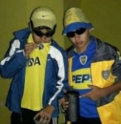 two young men standing next to each other wearing yellow and blue shirts with hats on