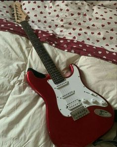 a red and white guitar laying on top of a bed