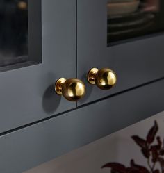 two brass knobs on the side of a gray cabinet with glass doors and windows