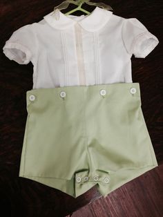 Spring green button-on pants with ecru poly/cotton shirt. The shirt has a centered lace insertion framed by pintucks on either side Peter pan collar and sleeves feature piping and a little bit of masculine lace. Extra length on the shirt allows for extra-long wear as your little man grows. Shorts are closed with snaps at the crotch This outfit is perfect for Easter, portraits, weddings, or any special occasion! He will be more than adorable! Available in multiple sizes; pants available in multip Green Short Sleeve Sets With Buttons, Classic Collared Sets For Spring, Classic Spring Sets With Collared Shape, Elegant Fitted Sets With Pintucks, Green Summer Sets With Button Closure, Green Cotton Sets With Buttons, Classic White Collared Sets, Classic Cream Summer Sets, Classic Short Sleeve Sets For Spring