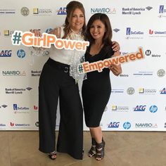 two women standing next to each other in front of a wall with the words girl power on it