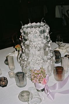 a table topped with lots of glass vases and flowers on top of a white table cloth