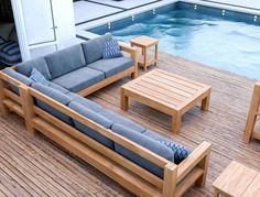 a couch and table sitting on top of a wooden deck next to a swimming pool