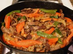 a skillet filled with meat and vegetables on top of a stove