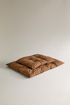 two pillows sitting on top of each other in front of a white wall and floor