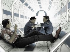 two men sitting on top of an escalator talking to each other in front of a mirror