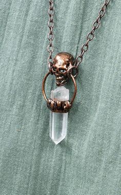 “Life's true face is the skull.” The Calvaria Clear Quartz Skull Necklace is made from a beautiful raw quartz crystal that has been then encased in a handmade sculptured solder setting made into a skull. The necklace secures with a ring on either side of the pendant and includes a 70cm long antique bronze chain. These necklaces are hand made and each is beautifully unique. Clear Quartz is a stone of power that amplifies any energy for intention, enabling you to find your ultimate potential at all stages of life, it is infused with purpose which is particularly useful if you lack direction or feel lost in life, allowing you to acknowledge the unique gifts you have to offer the world. Known as the master healer, Clear Quartz harmonises all of the chakras, bringing them into balance and align Cottagecore Witch, Lost In Life, Stages Of Life, Witch Vibes, Clear Quartz Necklace, Feel Lost, Raw Quartz Crystal, Boho Crystal, Quartz Crystal Pendant