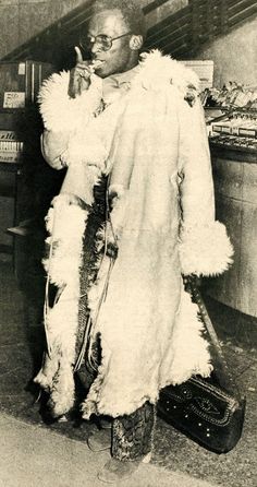 an old photo of a man dressed in fur and holding a cell phone to his ear