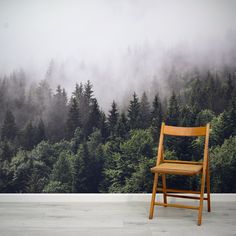 a wooden chair sitting in front of a forest wallpapered with fog and trees