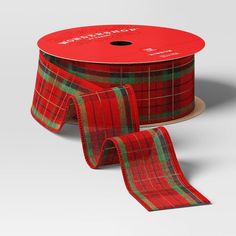 a roll of red and green plaid ribbon next to a roll of red and green checkered ribbon