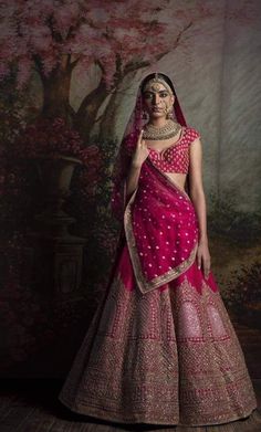 a woman in a pink and gold lehenga