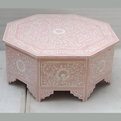 a pink wooden table with an intricate design on it