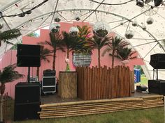 a stage set up with palm trees, speakers and sound equipment in front of a pink wall