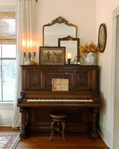 an old piano sitting in the corner of a room next to a mirror and window