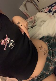 a woman laying on top of a bed with her stomach covered in stars and tattoos