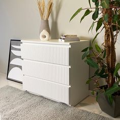 a white dresser sitting next to a potted plant