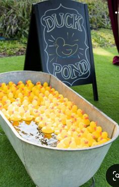 a metal tub filled with lots of oranges next to a chalkboard sign that says duck pond