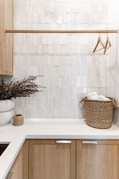 a white tiled kitchen with wooden cabinets and counter tops, an ironing board on the wall