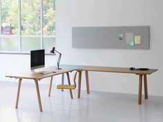 a computer desk with a monitor and keyboard on it in an empty room next to windows