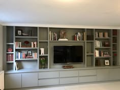 a living room with bookshelves and a flat screen tv mounted on the wall