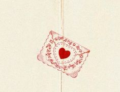 a red heart is hanging on a white wall with a lace doily around it