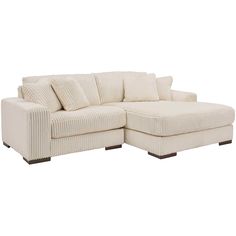 a white sectional sofa with pillows on it's back and arms, facing the corner